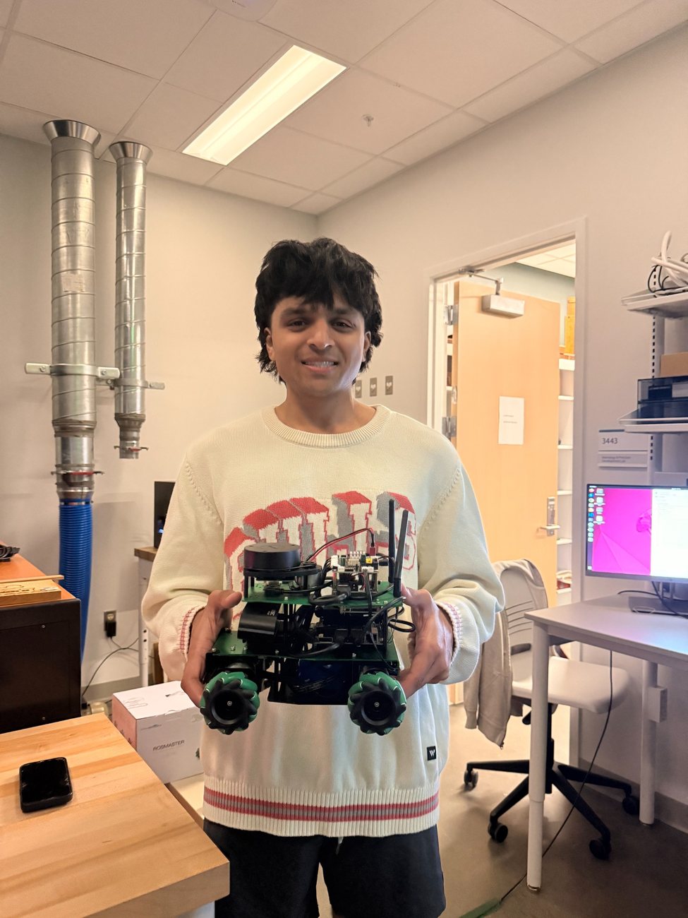 Hamza Khan holding an autonomous mobile robot in the lab